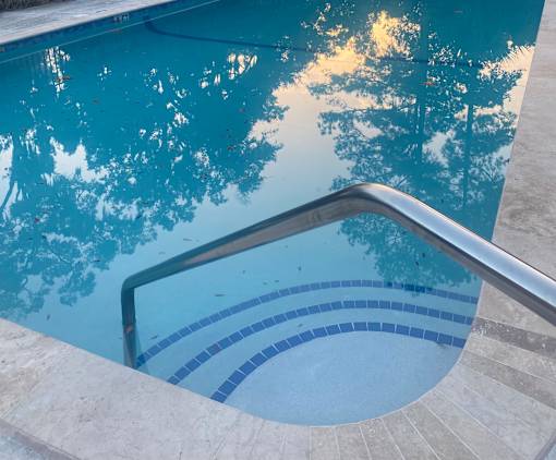 A pool with a metal handrail and blue tiles.