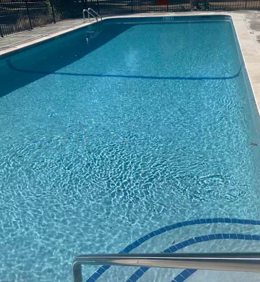A blue swimming pool with a metal railing.