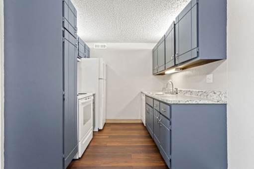 an empty kitchen with blue cabinets and a white refrigerator