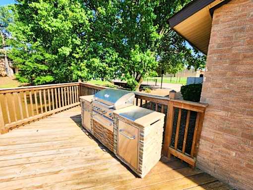 A wooden deck with a grill and a cooler on it.