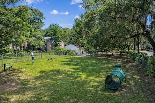 A playground with a slide and a green barrel in the foreground.
