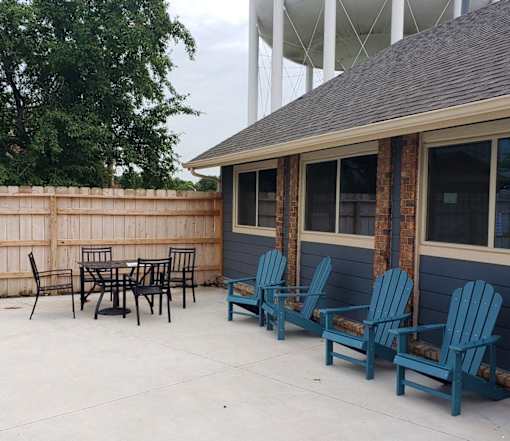 A patio with blue chairs and a table.