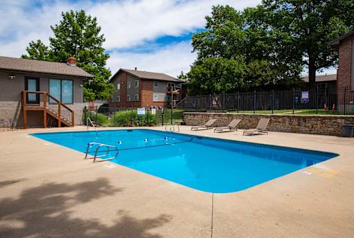 A blue swimming pool surrounded by a fence and trees.