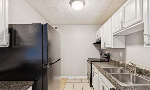 A kitchen with a black refrigerator and white cabinets.
