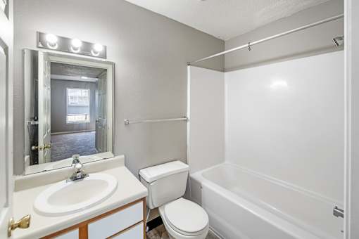 A white bathroom with a toilet, sink, and bathtub.