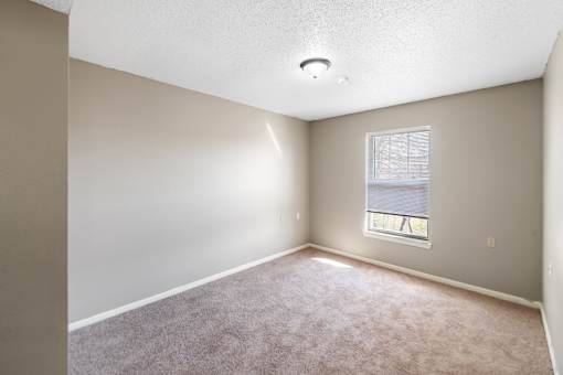 A room with a window and carpeted floor.