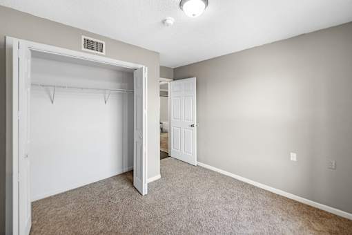 A room with a white door and a carpeted floor.