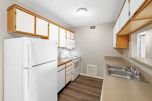 A kitchen with white appliances and wooden cabinets.