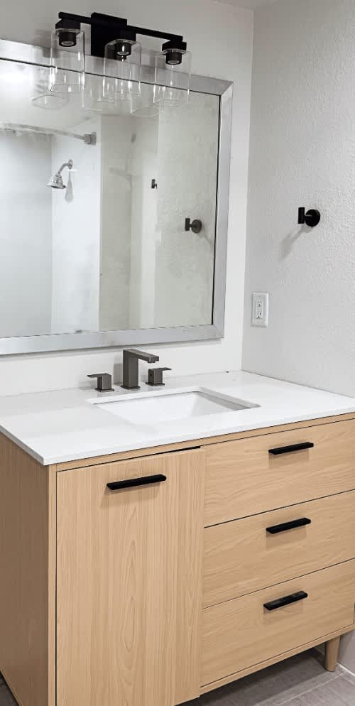 A bathroom vanity with a sink and a mirror above it.