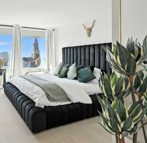 A bedroom with a large bed and a view of a city skyline.