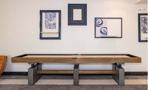 A pool table with three picture frames on the wall.
