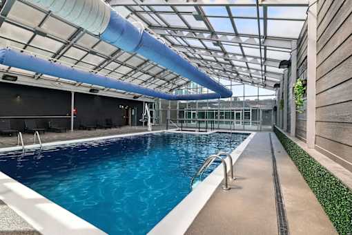 A large indoor swimming pool with a blue tinted water.