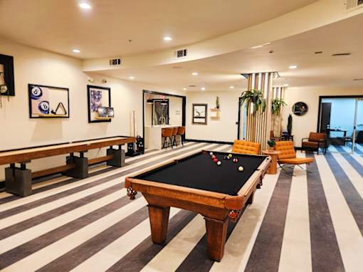 A pool table is in the middle of a room with striped flooring.