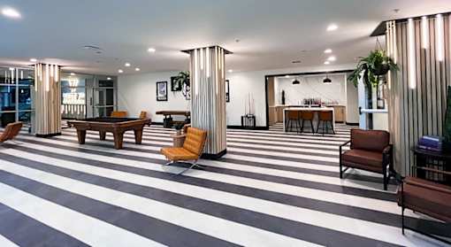A black and white striped floor in a room with a long table and chairs.
