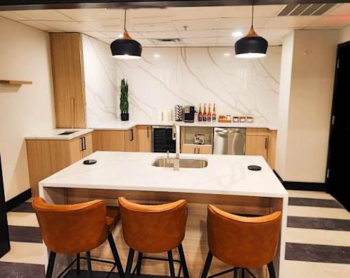 A kitchen with a white countertop and brown chairs.