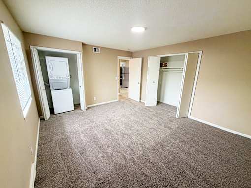 A room with a carpeted floor and a white refrigerator.