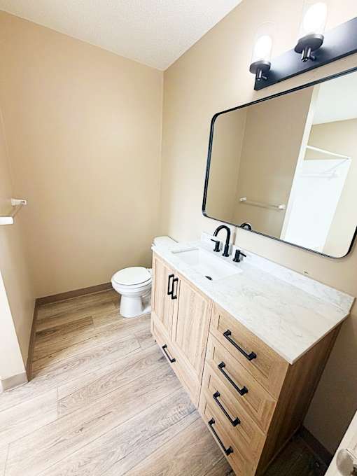 A bathroom with a wooden vanity and a mirror above it.