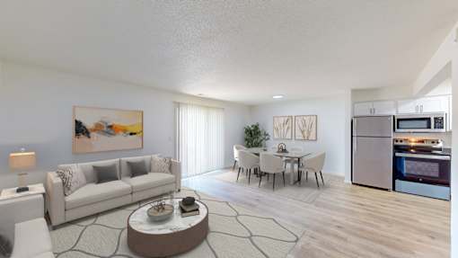 A modern living room with a grey sofa, a coffee table, and a kitchen in the background.