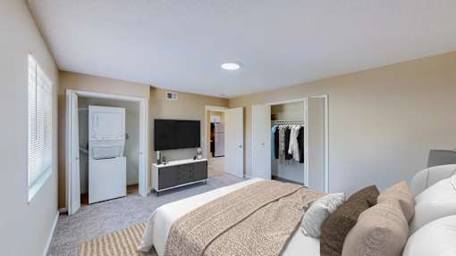 A bedroom with a bed, a television, and a refrigerator.