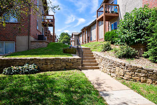 A stone wall and staircase lead up to a building with a balcony.