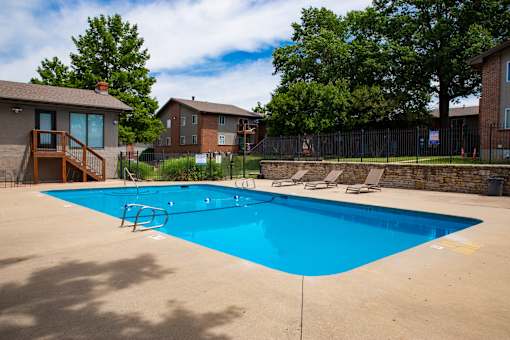 A blue swimming pool surrounded by a fence and trees.
