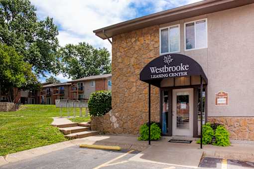 The front of the Westbrooke Leasing Center is shown with a stone facade and a green lawn.