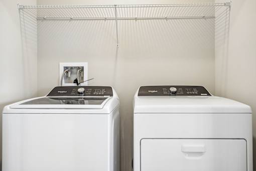 Two white front loading washing machines in a laundry room.