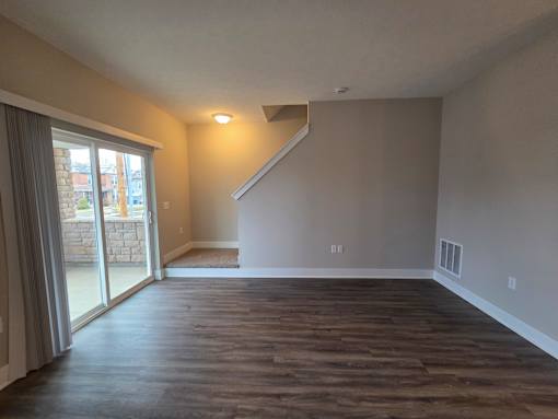 Townhome living area with walkout patio and stairs leading to second level s at Flats at Sugar Run Apartments, Delaware, OH