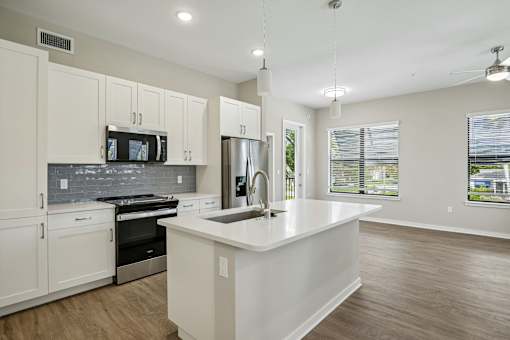 A kitchen with white cabinets and a stainless steel refrigerator.