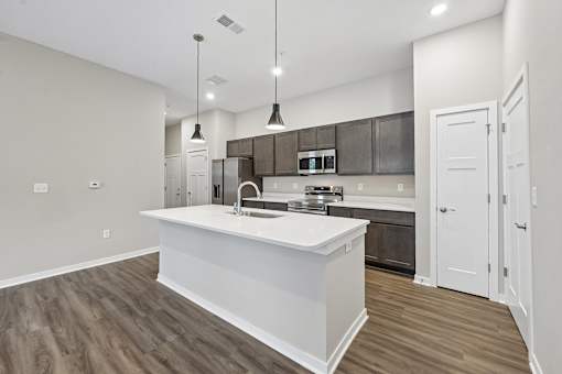 A modern kitchen with a white island and wooden floors.