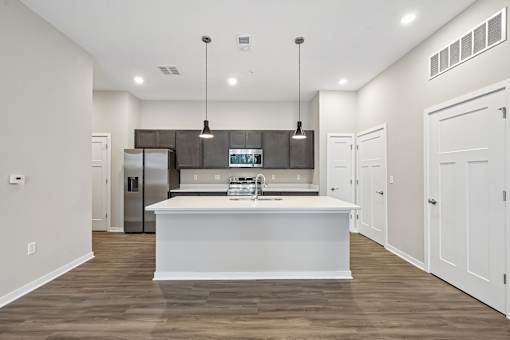 A modern kitchen with a white island and wooden floors.