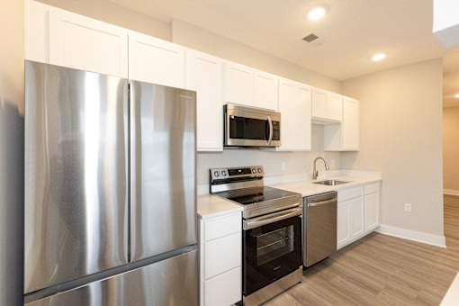 A modern kitchen with stainless steel appliances and white cabinets.at Tiffany Flats, Columbus