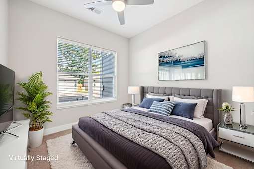 A bedroom with a bed, a television, a potted plant, and a painting on the wall.