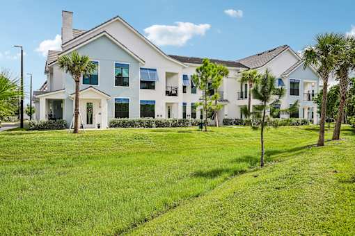 A white house with a blue roof and a green lawn in front.