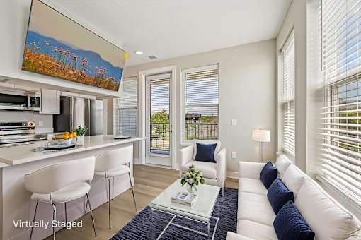 A living room with a white couch and a painting on the wall.
