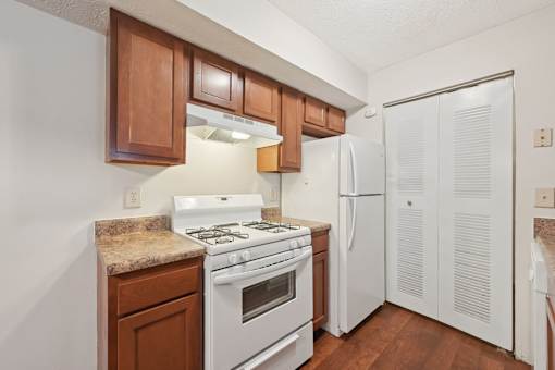A kitchen with white appliances and wooden cabinets.