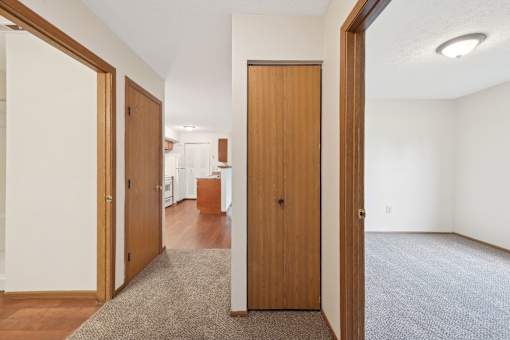 A hallway with a carpeted floor and a brown door.