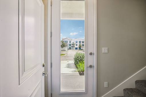 A white door with a glass window showing a street view.