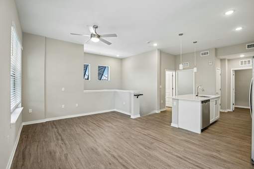 A spacious room with a kitchenette and a ceiling fan.