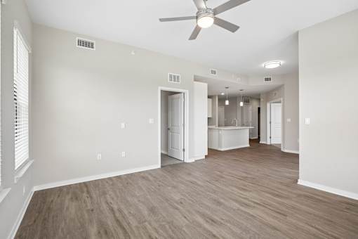 A room with a ceiling fan and light fixture, and a doorway leading to another room.