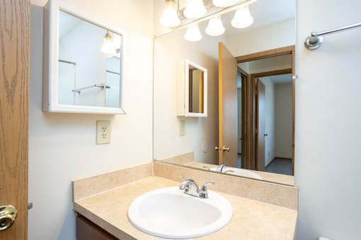 A bathroom with a sink, mirror, and light fixture.