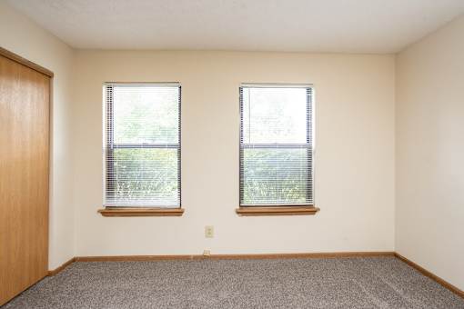 A room with two windows and a carpeted floor.