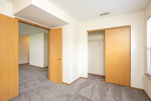 A room with two open doors and carpeted flooring.