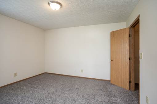 A room with a carpeted floor and a wooden door.