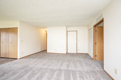 A room with a carpeted floor and two doors.