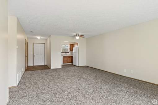 A spacious living room with a carpeted floor and a ceiling fan.