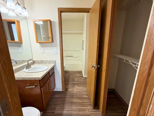 A bathroom with a toilet, sink, mirrors and a shower.