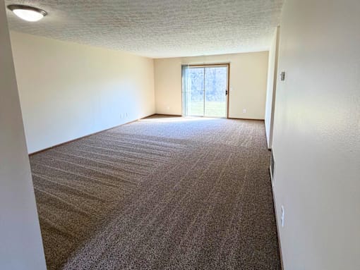 A carpeted room with a door leading outside.