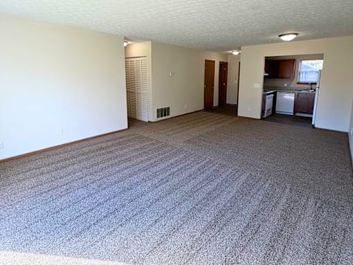 A large, empty room with a carpeted floor and white walls.