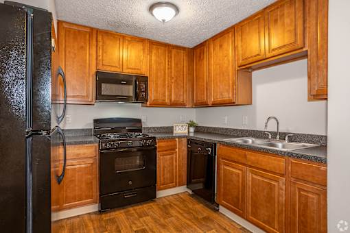 A kitchen with wooden cabinets and black appliances.
